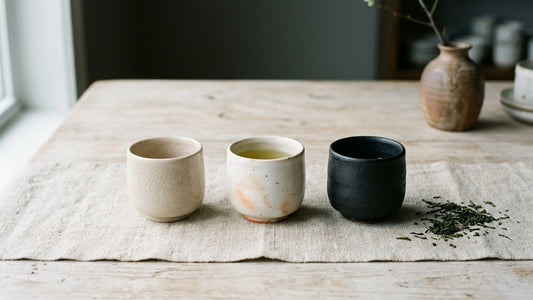 Three Japanese yunomi tea cups in crackle cream, warm blush, and matte black glazes