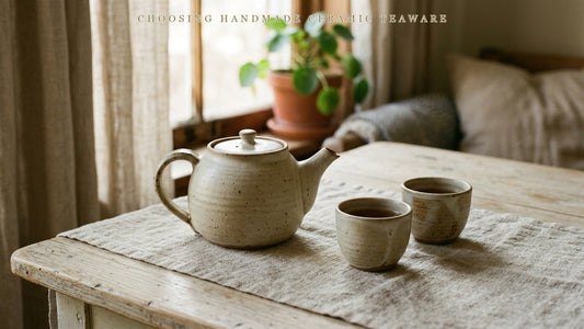 A handmade ceramic teapot with throwing rings and two handmade cups showing natural glaze variation
