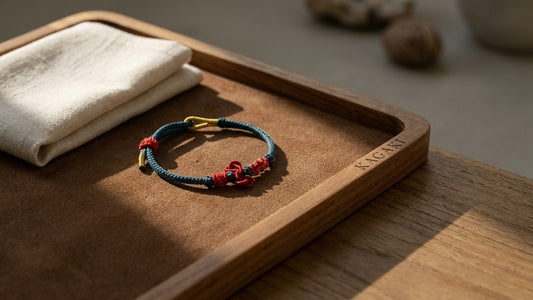 A KAGAKI handmade Tibetan-inspired meditation cord bracelet arranged on a teak studio tray in soft daylight, shown as a hero image for a studio guide to meditation bracelets.