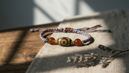 KAGAKI Pilgrim Tibetan Dzi cord bracelet — close editorial macro of the slim cord and dzi bead in soft natural light, shown as the hero image for a guide on Tibetan bracelet colors meaning.