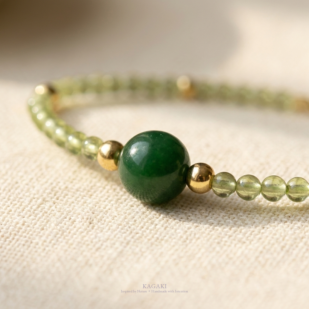 KAGAKI green jade crystal bracelet with dark green jade focal bead and gold spacers — detail close-up editorial view.