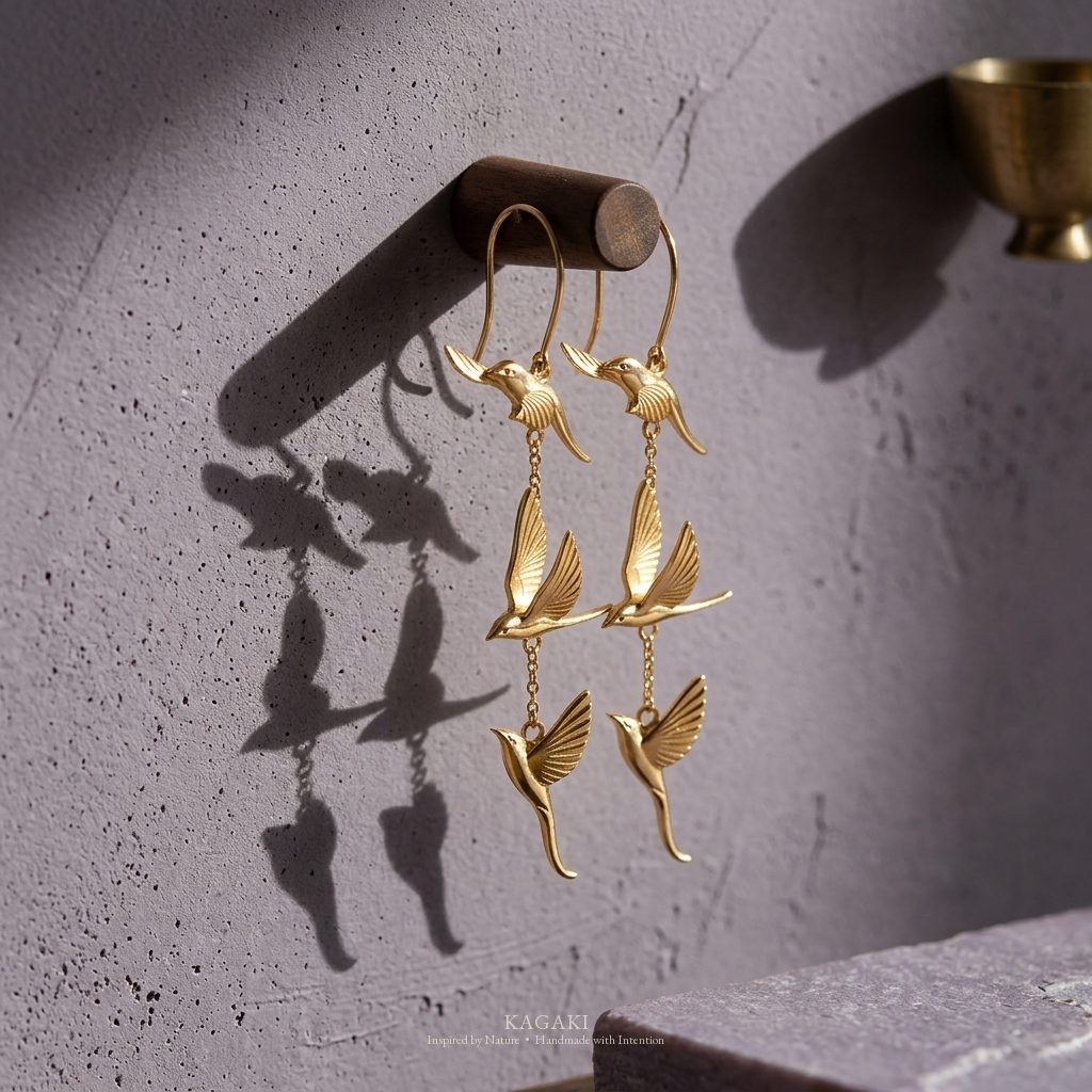 KAGAKI gold flying-swallow handmade dangle earrings — altar still-life editorial view.
