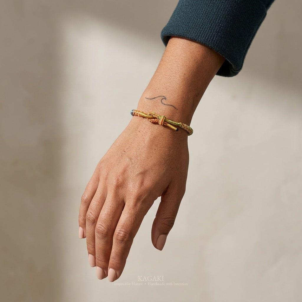 KAGAKI handmade cord bracelet rainbow gradient braided cord bracelet — full rainbow + gold thread, luxury jewelry editorial wearing shot.