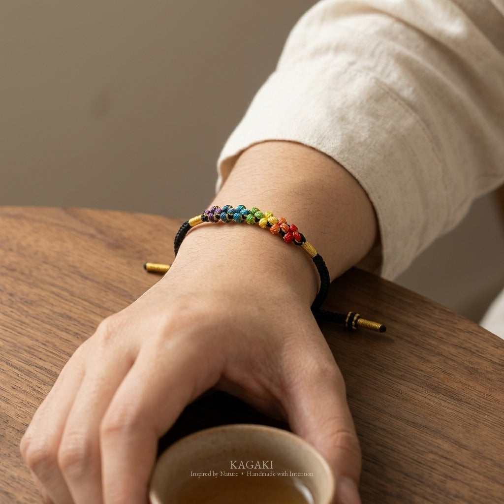 KAGAKI handmade cord bracelet rainbow sakura knot cord bracelet — black with rainbow knotted florals, wrist wearing image.
