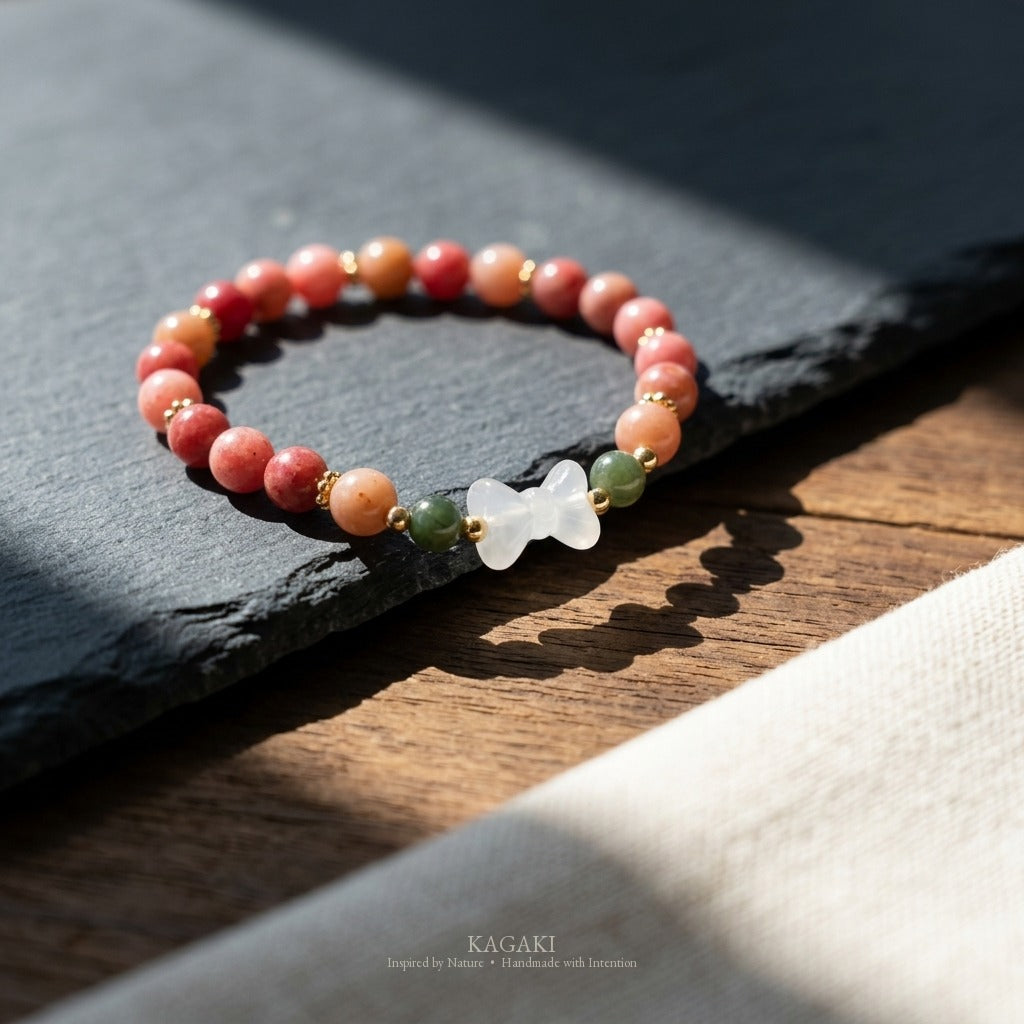 KAGAKI handmade crystal bracelet pink stone beaded bow stretch bracelet — pink + white + gold, editorial styled scene.