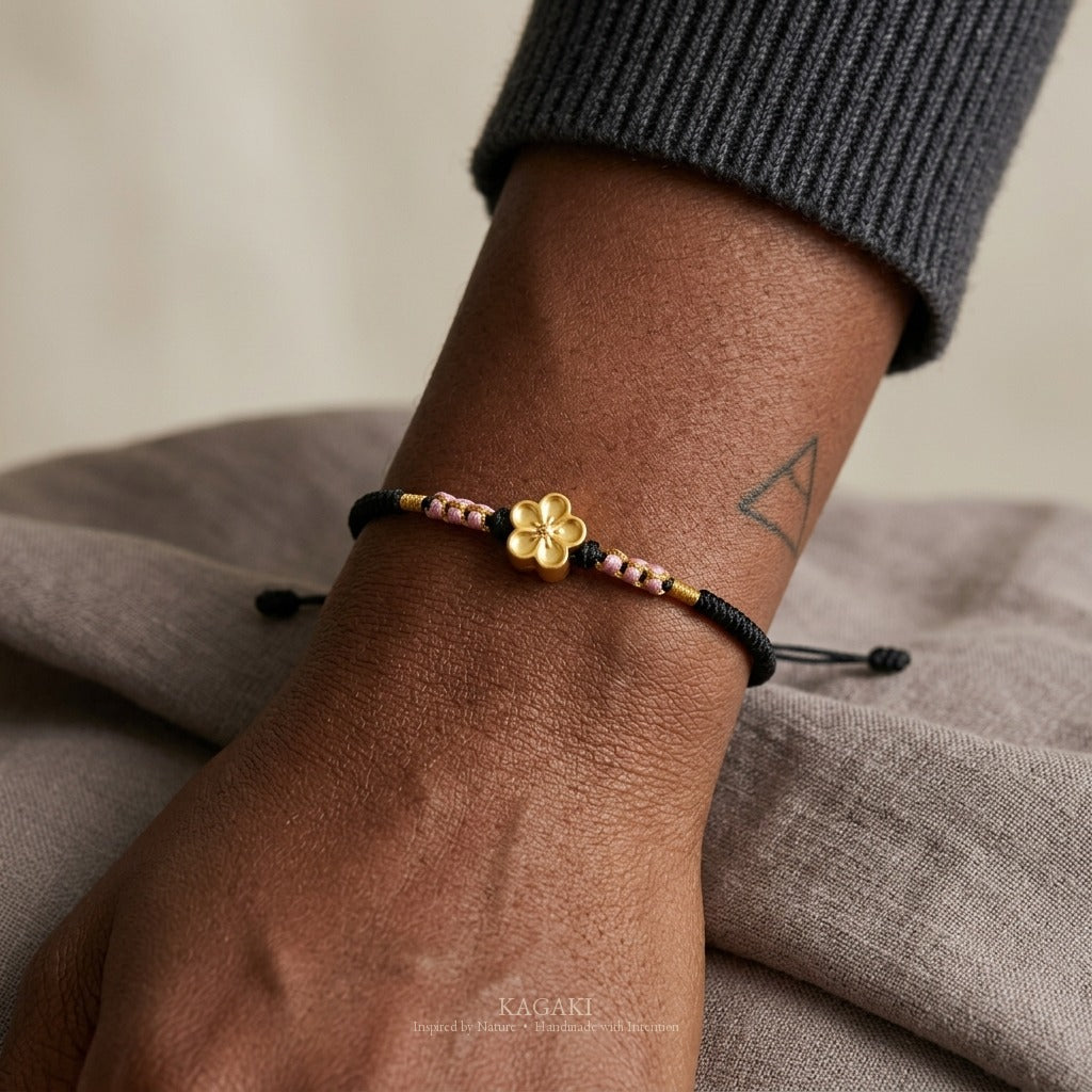 KAGAKI handmade cord bracelet sakura plum blossom cord bracelet (ink & petal) — black / green / red with gold accent, natural lifestyle wrist detail.