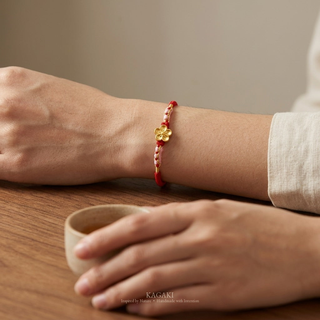 KAGAKI handmade cord bracelet sakura plum blossom cord bracelet (vermilion & petal) — black / green / red with gold accent, wrist wearing image.