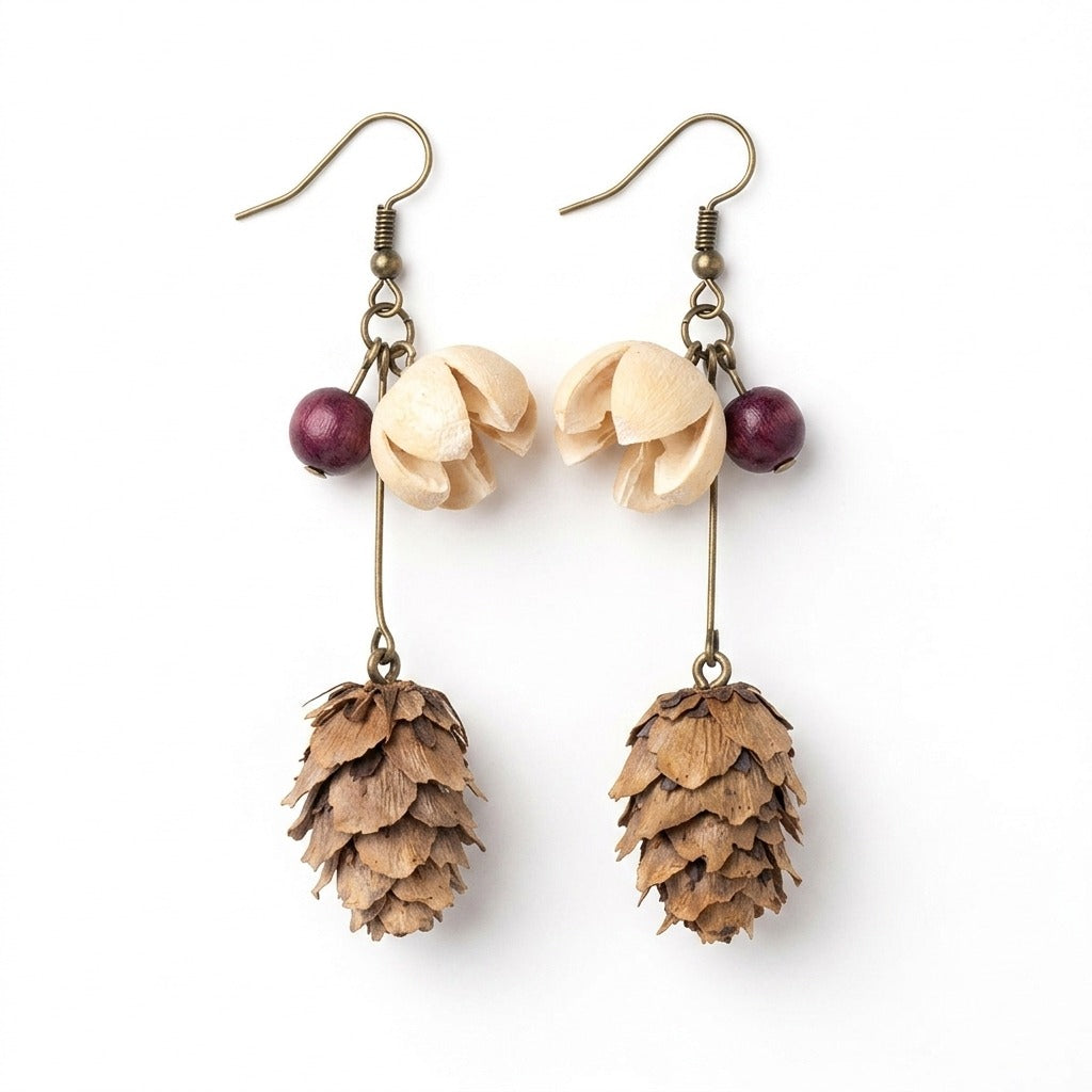 KAGAKI handmade earrings combining antique-brass hardware with natural dried elements — purple wood bead, cream petal cluster, dried cone pod — on pure white background.