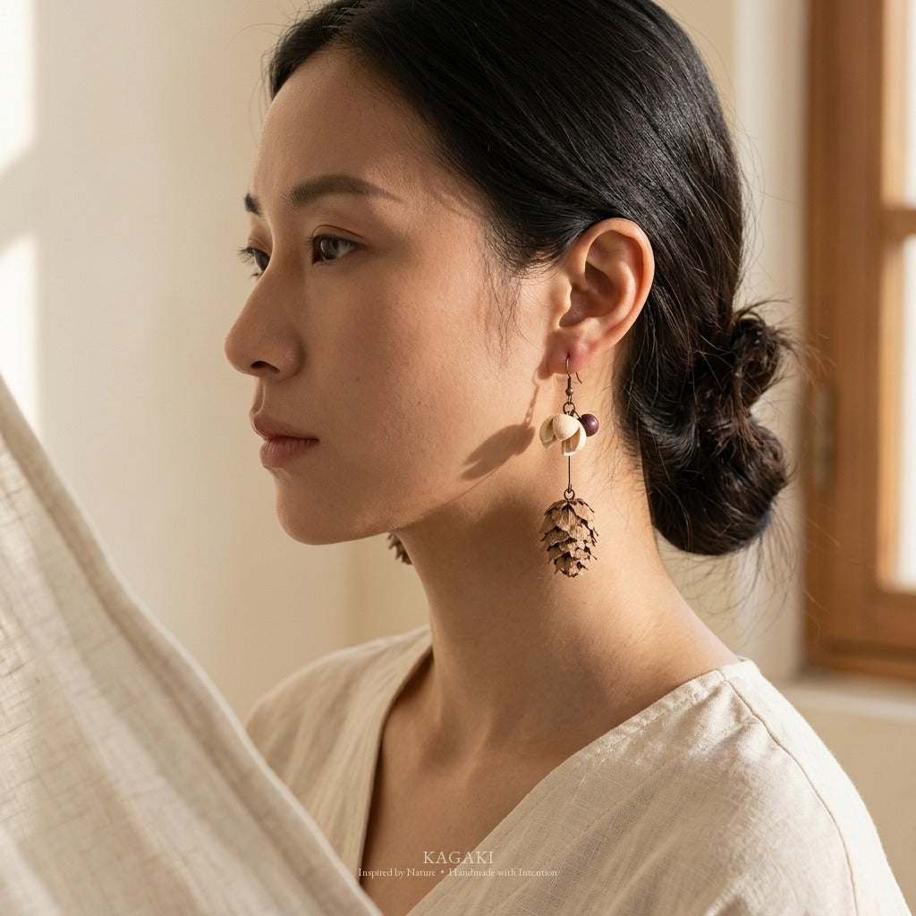 KAGAKI dried-botanical earrings worn in pure side profile, with strong window-light shadow on the cheek and jaw — quiet morning-meditation portrait.