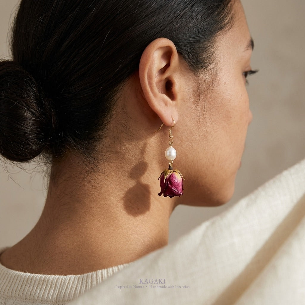 KAGAKI dried rose pearl earring shown worn on ear in back three-quarter view with low bun, pearl and rose visible against ivory knit shoulder