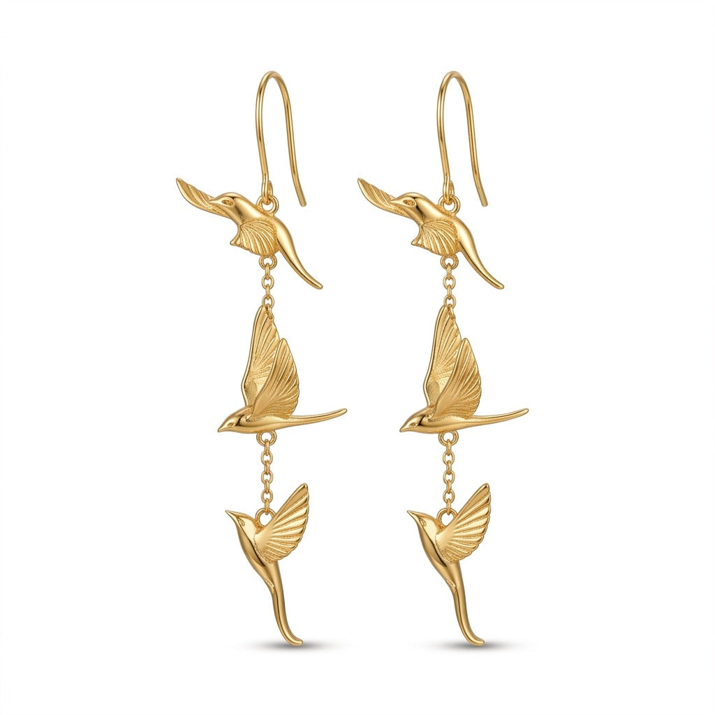 KAGAKI handmade gold dangle earrings featuring three stylized flying swallow charms, photographed on pure white background as refined spiritual jewelry.