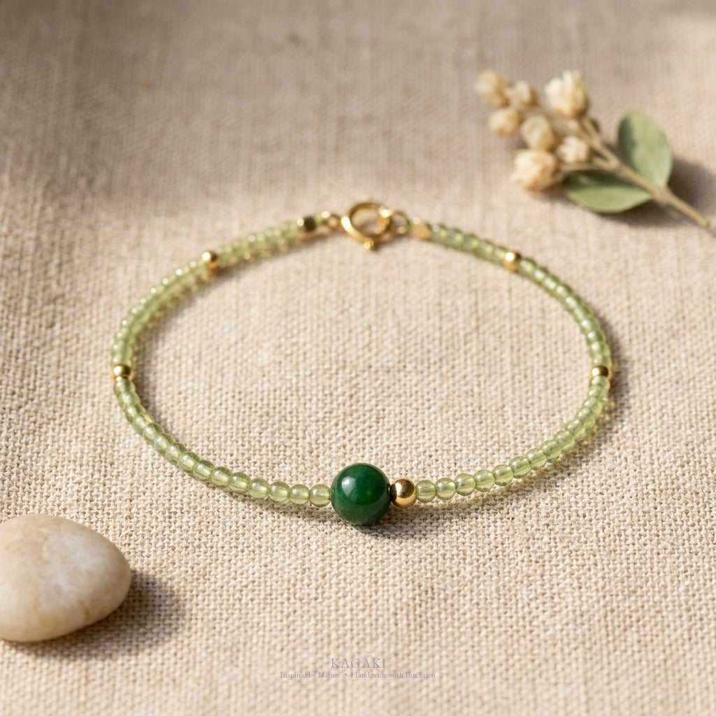 KAGAKI green jade crystal bracelet in a soft beige linen still-life with dried botanicals — handmade spiritual jewelry.