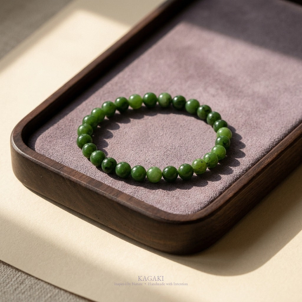 KAGAKI spinach-green jade bracelet on a dark walnut tea tray with a dusty-lavender suede inset, soft natural daylight, calm editorial mood.